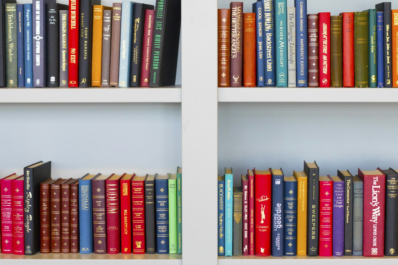 Colourful books arranged on white library shelves